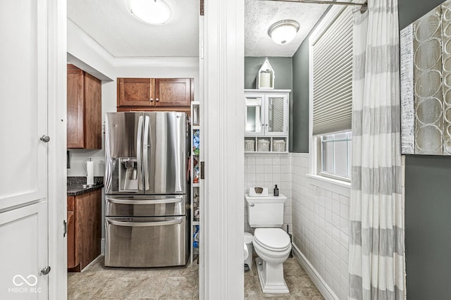 bathroom featuring tile walls, a textured ceiling, and toilet