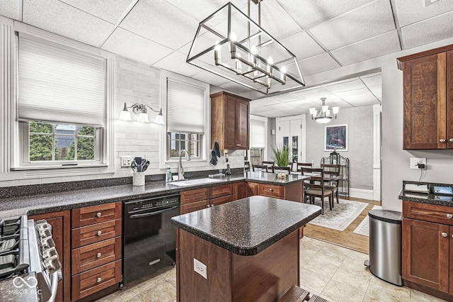 kitchen with sink, stainless steel gas stove, dishwasher, a kitchen island, and pendant lighting