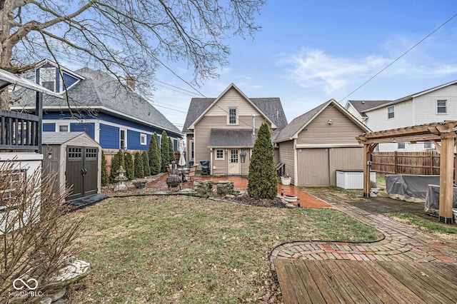 rear view of house with a shed, a yard, a pergola, a wooden deck, and a patio area