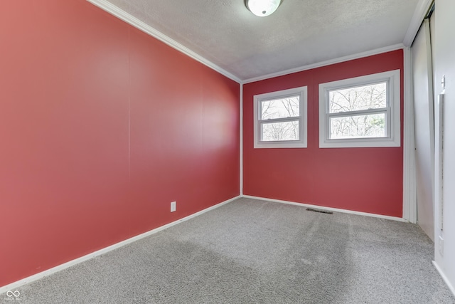 carpeted empty room with ornamental molding and a textured ceiling