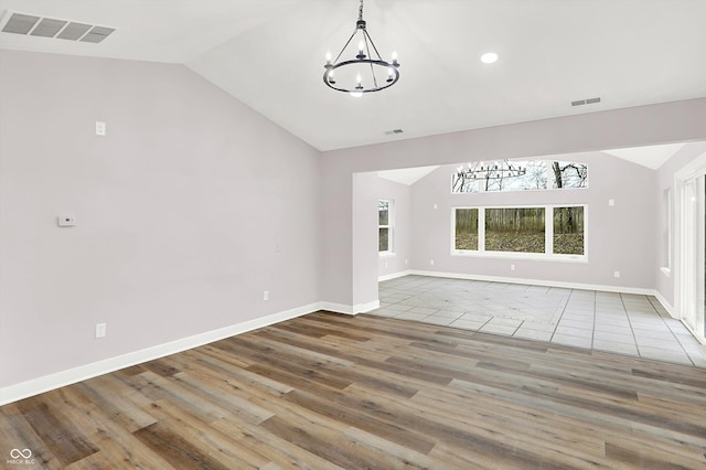 unfurnished living room featuring a notable chandelier, vaulted ceiling, and hardwood / wood-style floors