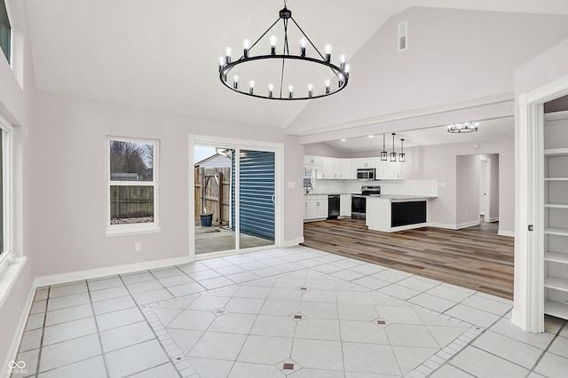 unfurnished living room with an inviting chandelier, high vaulted ceiling, and light tile patterned floors