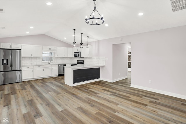 kitchen featuring white cabinetry, appliances with stainless steel finishes, hanging light fixtures, and backsplash