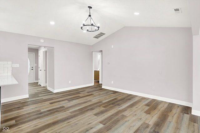 spare room featuring an inviting chandelier, lofted ceiling, and dark hardwood / wood-style floors