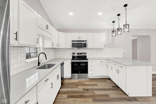 kitchen with sink, decorative light fixtures, kitchen peninsula, stainless steel appliances, and white cabinets