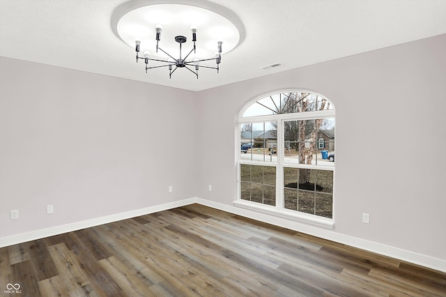 unfurnished dining area with hardwood / wood-style flooring, a textured ceiling, and a notable chandelier