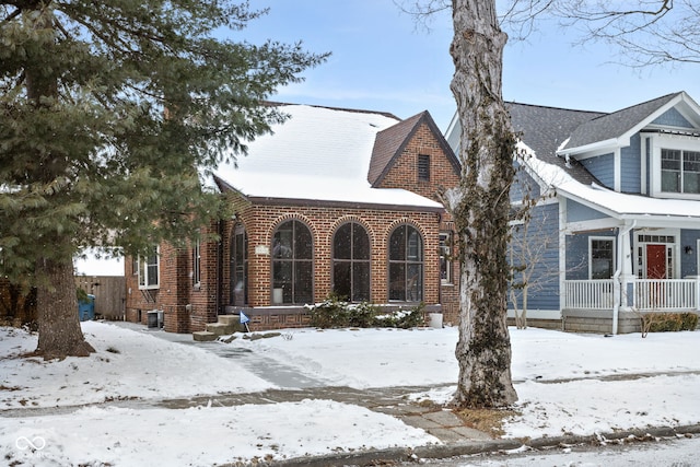 view of front of property featuring central AC, brick siding, and a porch