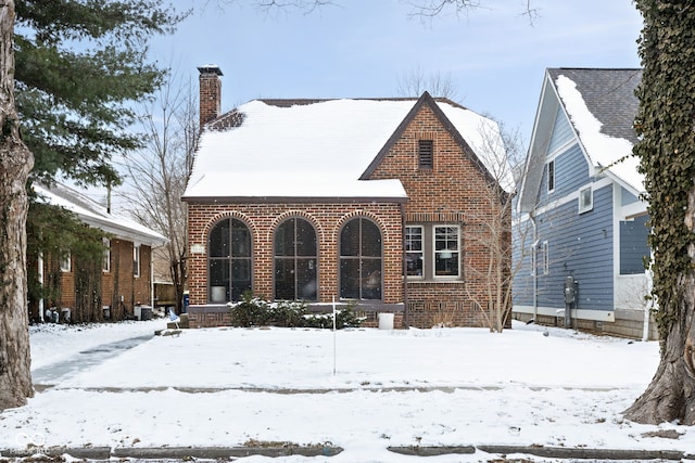 view of front of house with brick siding and a chimney