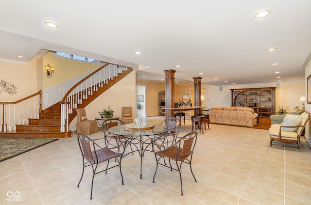 tiled dining space with ornamental molding and decorative columns