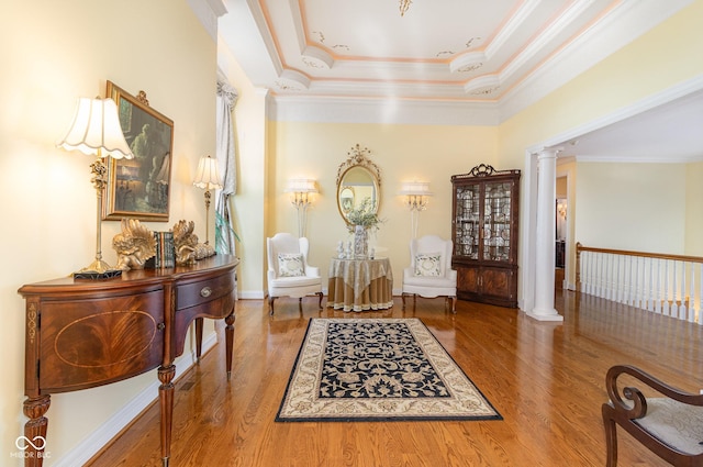 living area featuring hardwood / wood-style flooring, ornamental molding, and ornate columns