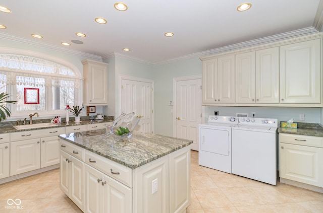 kitchen with sink, dark stone counters, a center island, independent washer and dryer, and crown molding