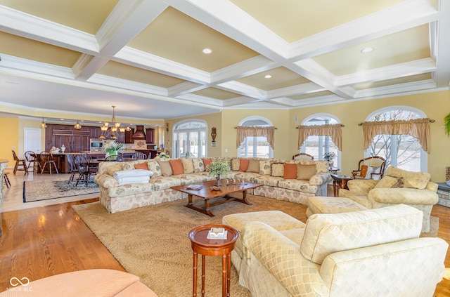 living room with beam ceiling, plenty of natural light, light wood-type flooring, and an inviting chandelier