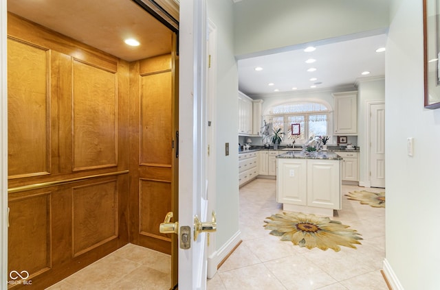 kitchen featuring ornamental molding, dark stone countertops, light tile patterned floors, and white cabinets