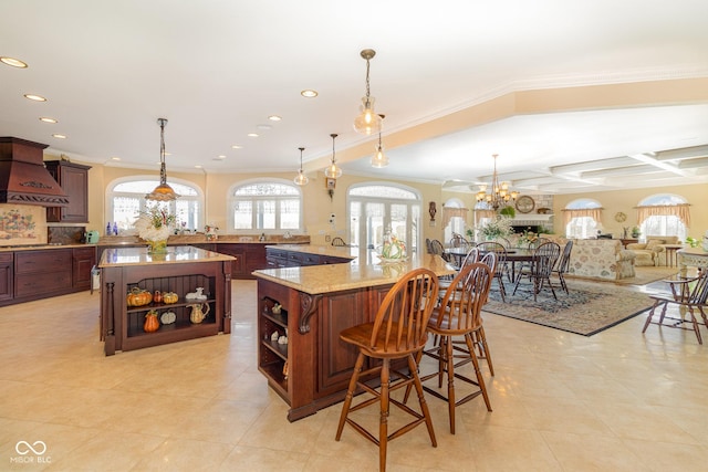 kitchen featuring a breakfast bar, hanging light fixtures, coffered ceiling, kitchen peninsula, and light stone countertops