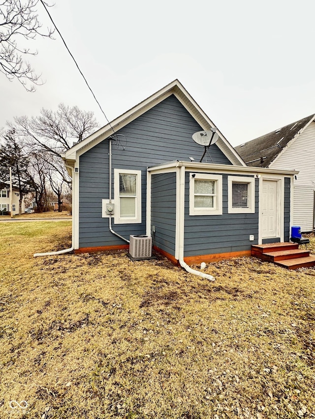 rear view of house with cooling unit and a lawn