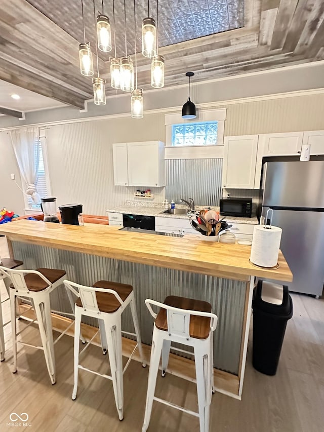 kitchen featuring white cabinetry, wooden counters, a kitchen breakfast bar, and black appliances