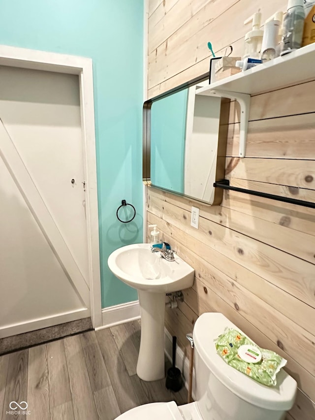 bathroom with toilet, wooden walls, and hardwood / wood-style flooring