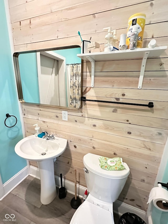 bathroom with hardwood / wood-style floors, wooden walls, and toilet