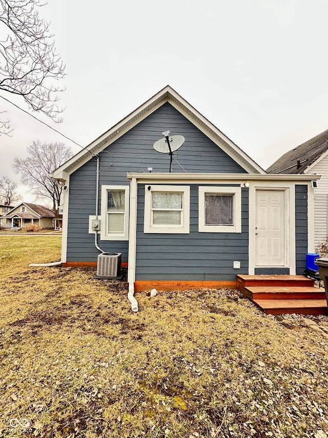 rear view of property with a yard and central air condition unit