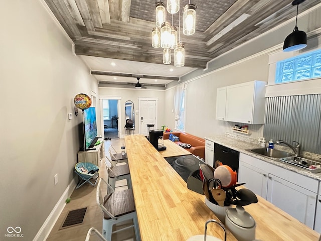 kitchen with sink, dishwasher, white cabinetry, light stone counters, and decorative light fixtures