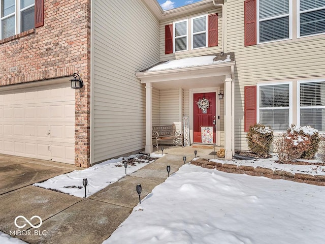 snow covered property entrance featuring a garage