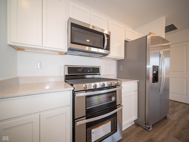 kitchen featuring stainless steel appliances, light countertops, visible vents, dark wood-type flooring, and white cabinets