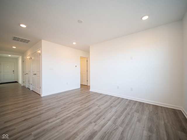 unfurnished room with recessed lighting, wood finished floors, visible vents, and baseboards