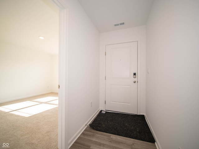 doorway featuring baseboards, visible vents, carpet flooring, and wood finished floors