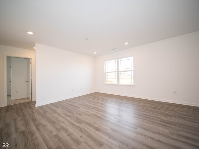 unfurnished room featuring baseboards, wood finished floors, and recessed lighting