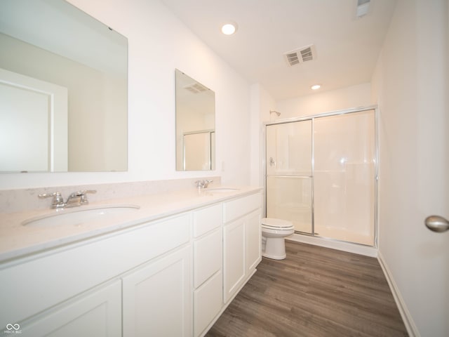 full bath featuring a stall shower, visible vents, toilet, wood finished floors, and a sink