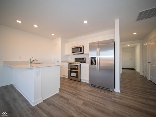 kitchen with dark wood-style floors, stainless steel appliances, visible vents, white cabinets, and a sink