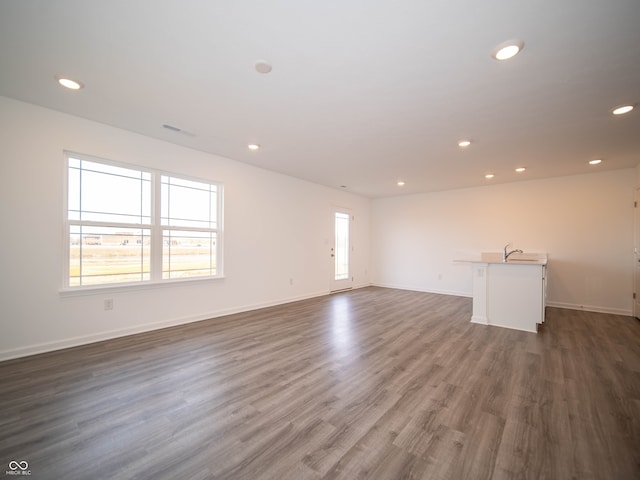 unfurnished living room featuring recessed lighting, dark wood-style flooring, a healthy amount of sunlight, and baseboards