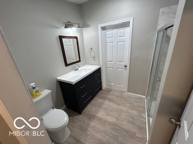 bathroom featuring vanity, hardwood / wood-style floors, toilet, and an enclosed shower