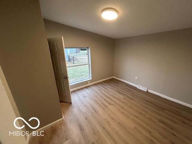 empty room featuring lofted ceiling and light hardwood / wood-style floors