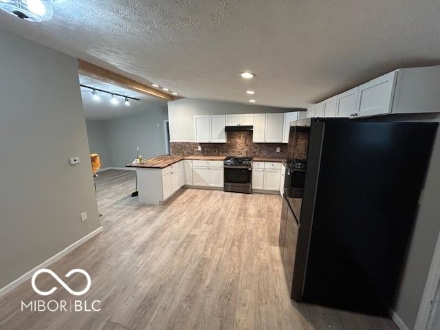 kitchen with white cabinetry, light wood-type flooring, fridge, stainless steel range with gas cooktop, and decorative backsplash