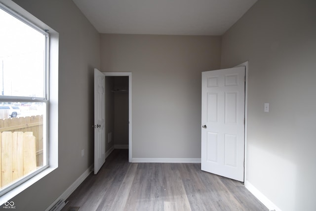 10 N Keystone Ave, Indianapolis, IN 46201 - unfurnished bedroom featuring a closet, light hardwood / wood-style floors, and multiple windows