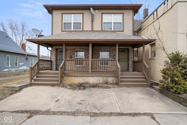 view of front of home with a porch, a shingled roof, and brick siding