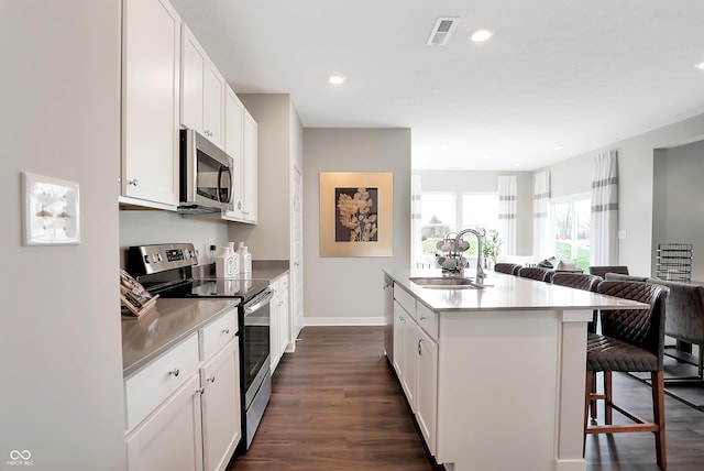 kitchen featuring a breakfast bar, sink, a center island with sink, stainless steel appliances, and white cabinets