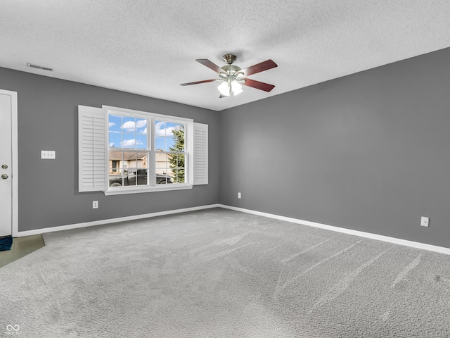 carpeted empty room featuring a ceiling fan, visible vents, and baseboards