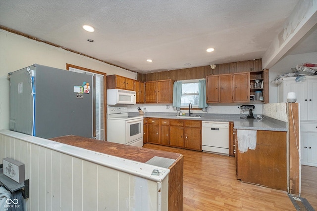 kitchen with white appliances, sink, light hardwood / wood-style flooring, and a textured ceiling