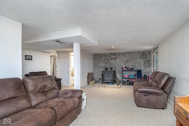 living room featuring carpet, a wood stove, and a textured ceiling