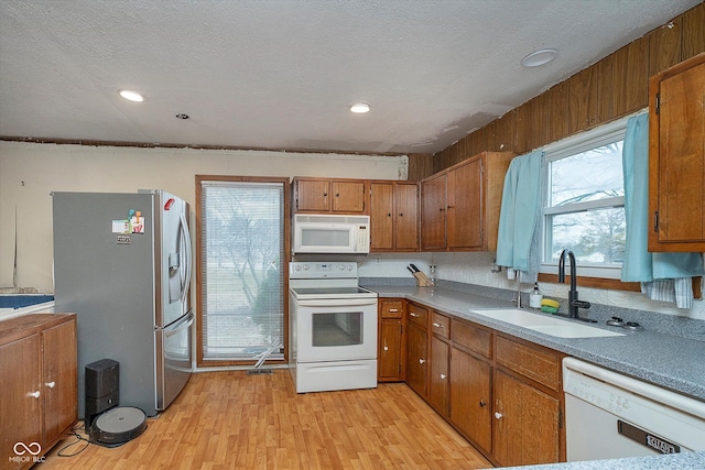 kitchen featuring white appliances, sink, light hardwood / wood-style flooring, and a textured ceiling