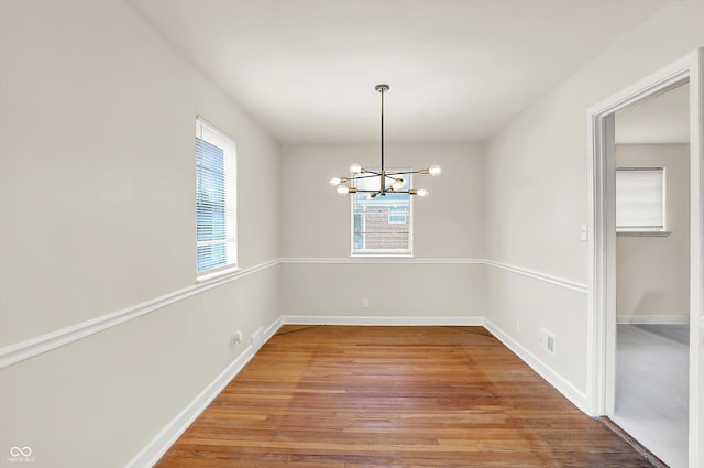 unfurnished dining area featuring wood-type flooring and a chandelier