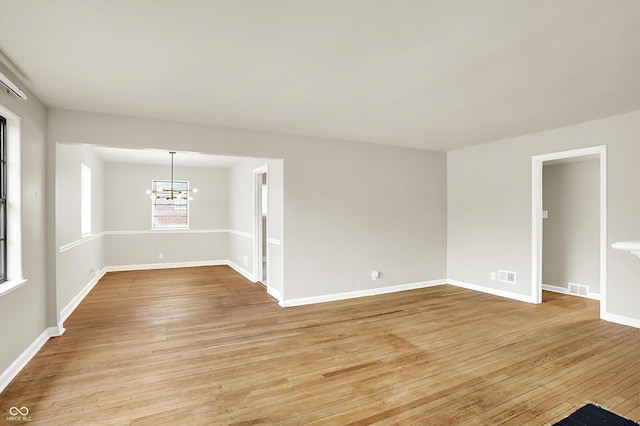 empty room with a chandelier and light wood-type flooring