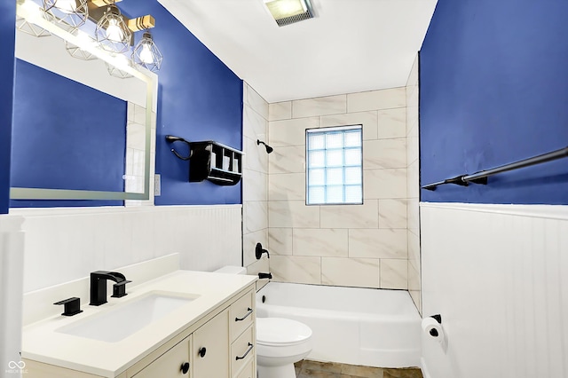 full bathroom featuring tiled shower / bath, vanity, and toilet