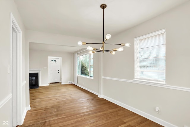 unfurnished living room with hardwood / wood-style floors and an inviting chandelier