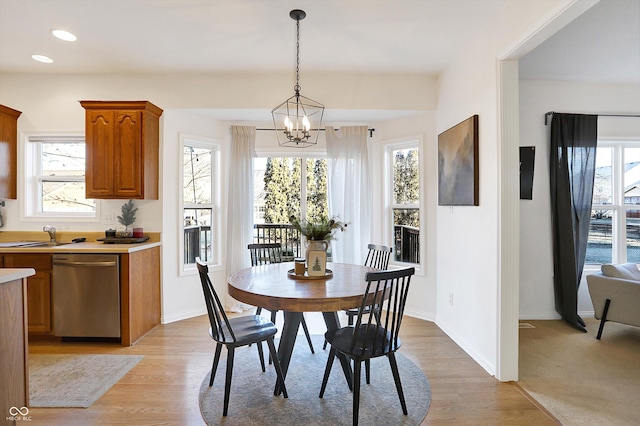 dining room with sink, an inviting chandelier, and light wood-type flooring