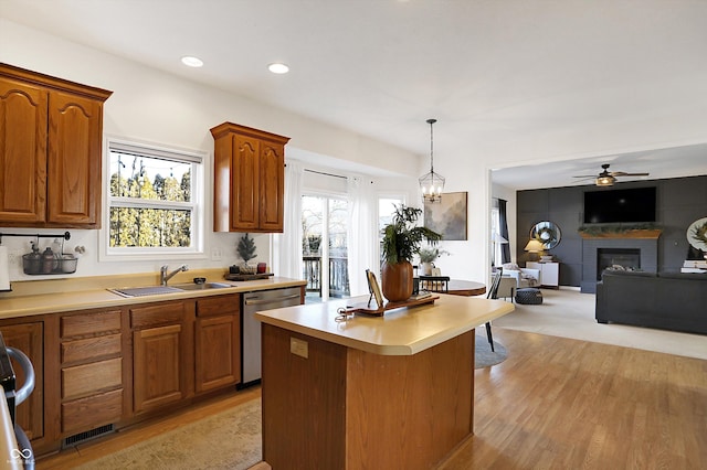 kitchen with sink, hanging light fixtures, a center island, a fireplace, and stainless steel dishwasher