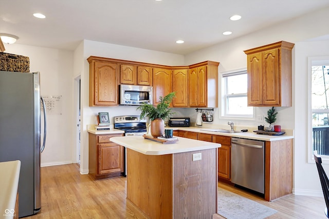 kitchen with stainless steel appliances, a kitchen island, and light hardwood / wood-style flooring