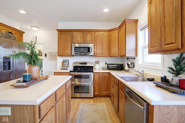 kitchen with appliances with stainless steel finishes, sink, and light hardwood / wood-style floors